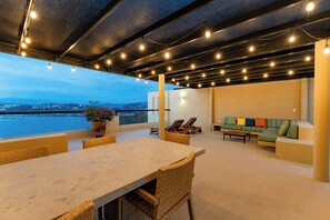 An outdoor seating area with a table and chairs, a sofa, and a view of the water. - Coastal Views and Private Beach Access (Huatulco)