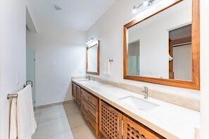 A modern bathroom with two sinks, wooden cabinets, and large mirrors. - Coastal Views and Private Beach Access (Huatulco)