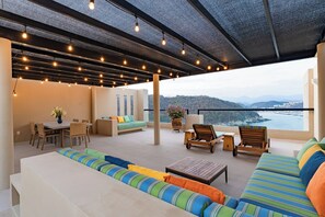 A spacious outdoor seating area with a view of the sea, a dining table with chairs, and a sofa with colorful cushions. - Coastal Views and Private Beach Access (Huatulco)