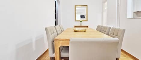 A modern dining room with a wooden table, six chairs, and a gold-framed mirror on the wall.