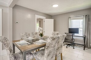 Un coin repas avec une table en bois, des chaises à motifs, un téléviseur et une fenêtre avec des rideaux.