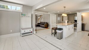 A spacious kitchen with a central island, a dining area with a sofa, and a view of the living room.