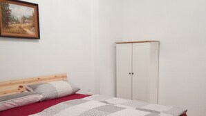 A bedroom with a wooden bed, a white wardrobe, and a painting on the wall. - To Senckenberg I by Satischni for two people with parking facilities (Görlitz)