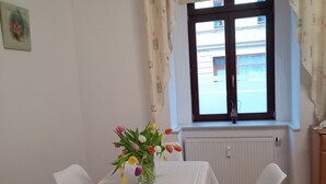A dining area with a table set for four, a vase of tulips, and a window with curtains. - To Senckenberg I by Satischni for two people with parking facilities (Görlitz)