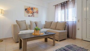 Un salon avec un canapé, une table basse, un tableau et une fenêtre avec des rideaux.