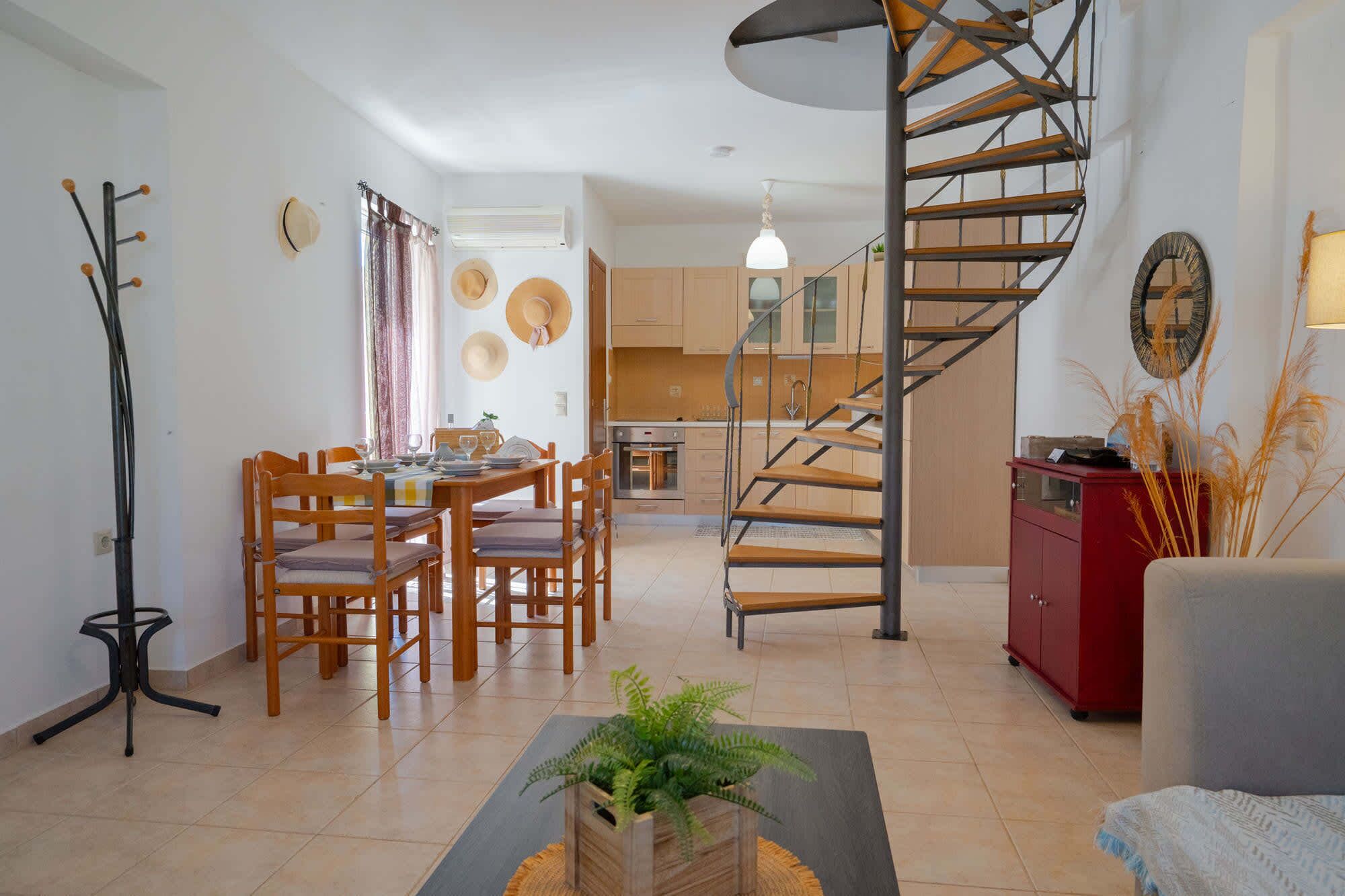 A modern living room with a dining area, a staircase, and a kitchen.