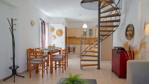 Un salon moderne comprenant un coin repas, un escalier et une cuisine.