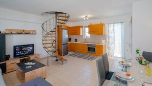 Un appartement moderne doté d’un escalier en colimaçon, d’une cuisine avec des meubles en bois, d’un coin repas avec une table en verre et d’un salon avec un canapé et une télévision.