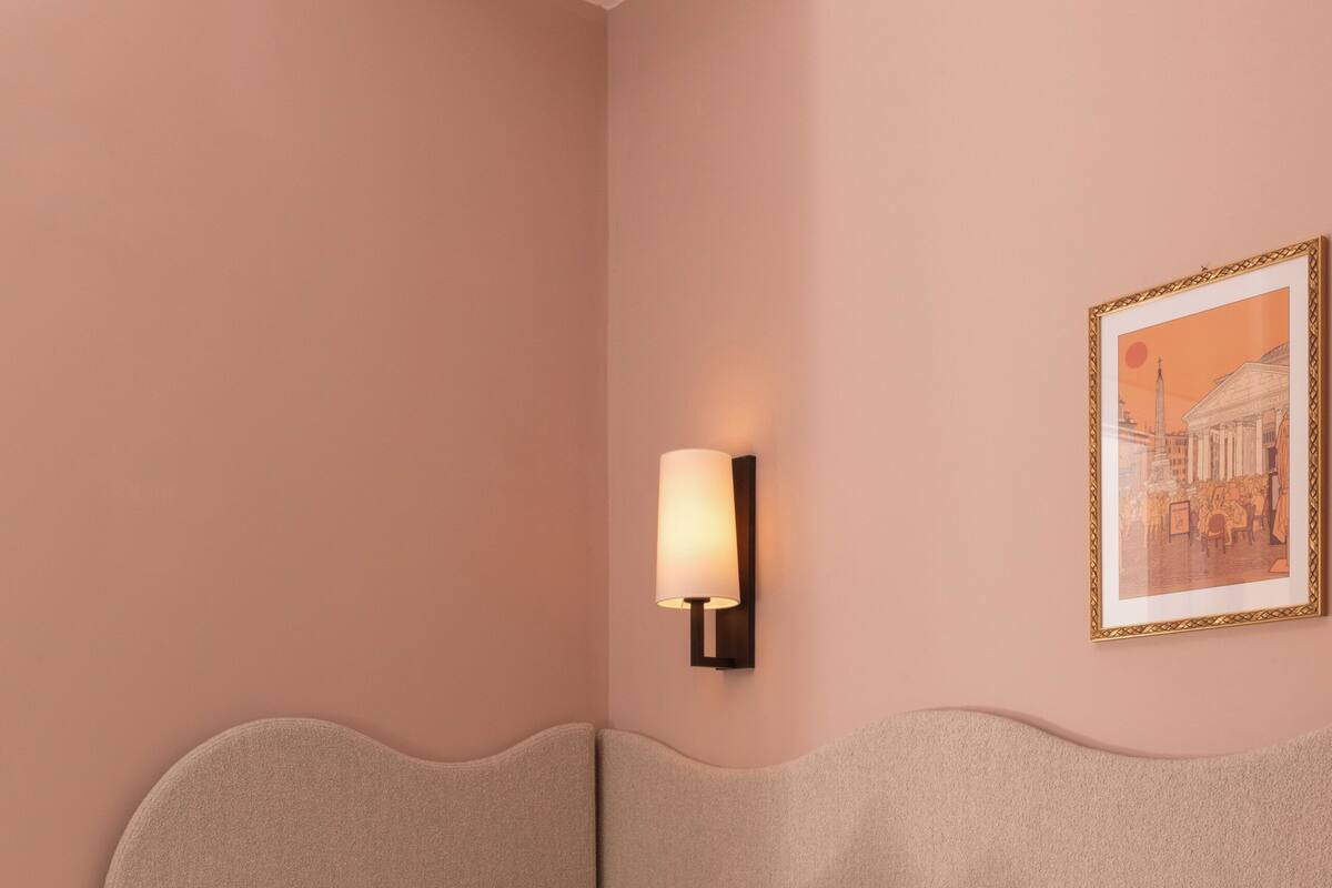 A neatly made bed with pillows, a bedside table with a lamp, and a framed picture on the wall.