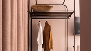 Un lit superposé avec une étagère suspendue, une table de chevet surmontée d’un plateau en marbre et une armoire en bois.