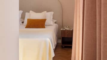 A bedroom with a bed, a nightstand, a lamp, and a curtain.