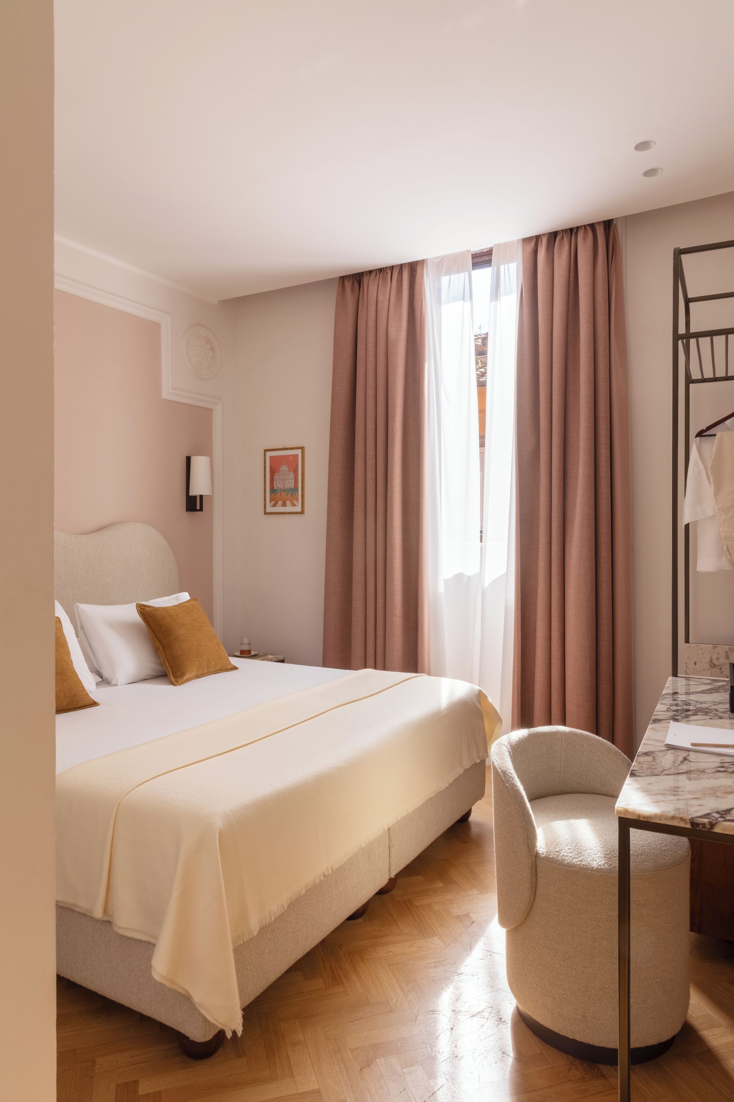 A hotel room with a bed, a chair, a desk, a lamp, and a window with curtains.