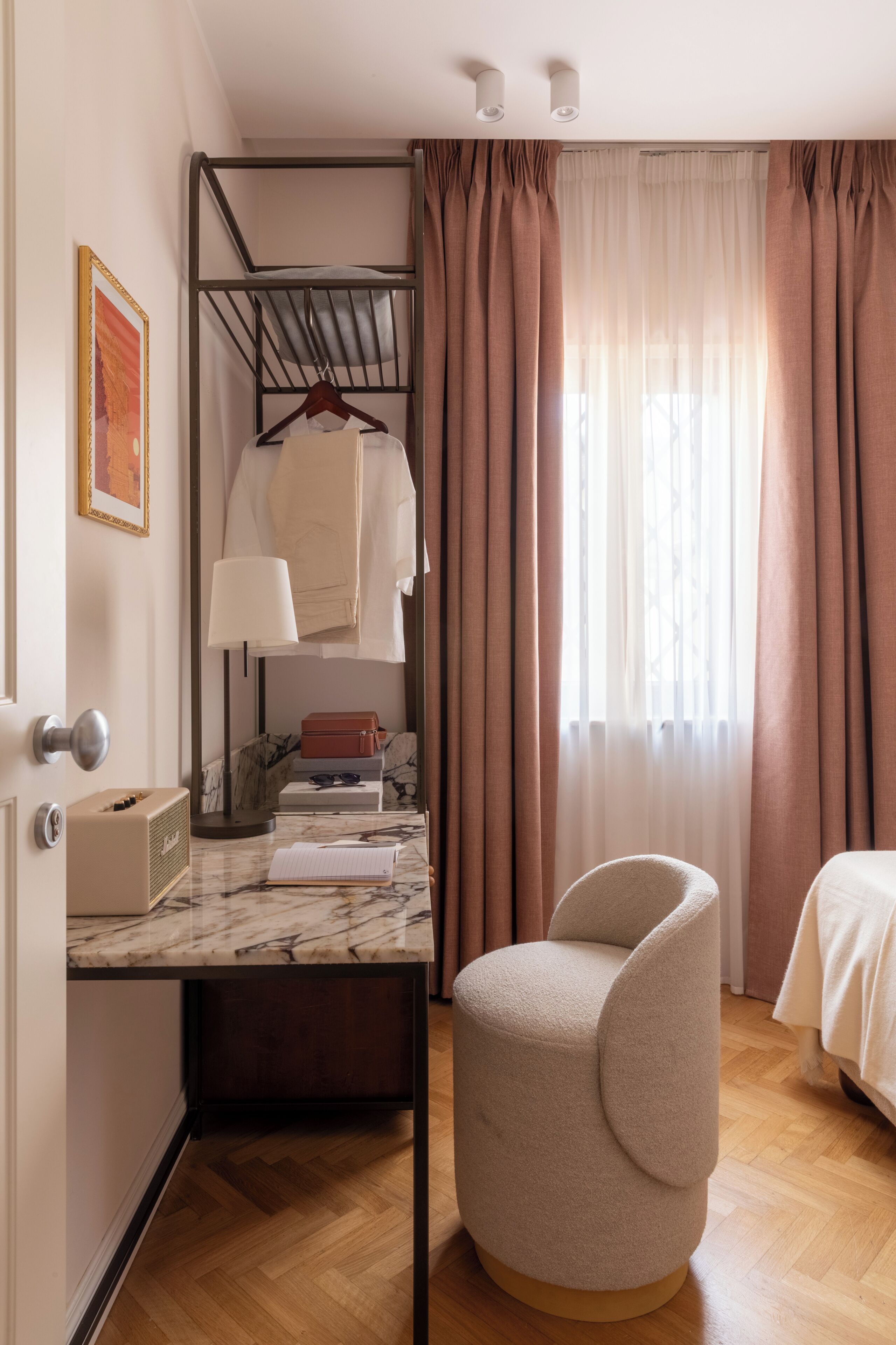 A compact room with a bunk bed, a desk with a lamp, a chair, and a window with curtains.