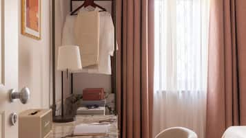 A compact room with a bunk bed, a desk with a lamp, a chair, and a window with curtains.