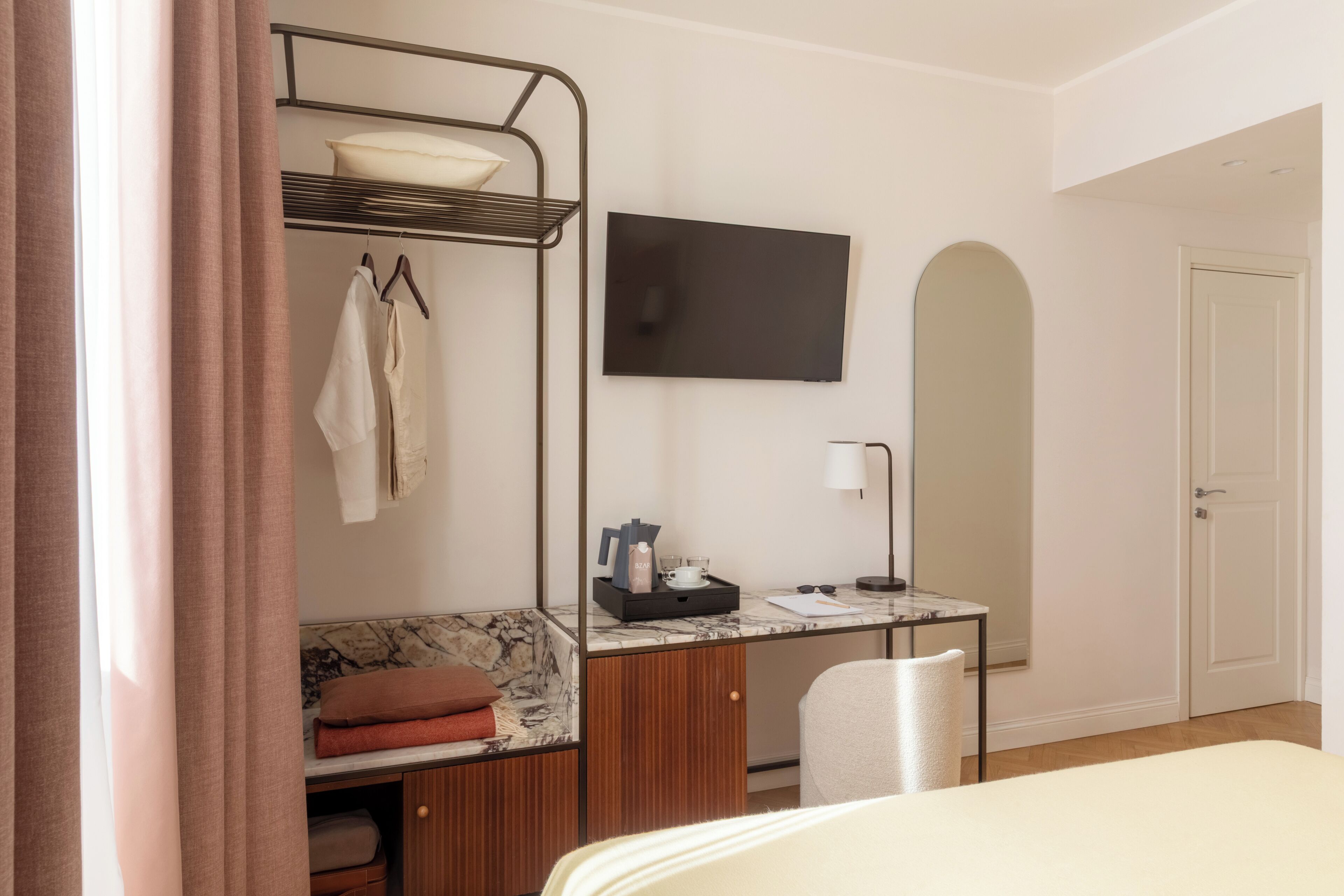 Una habitación de hotel con literas, un escritorio con televisión de pantalla plana, una silla, una cama y una puerta.