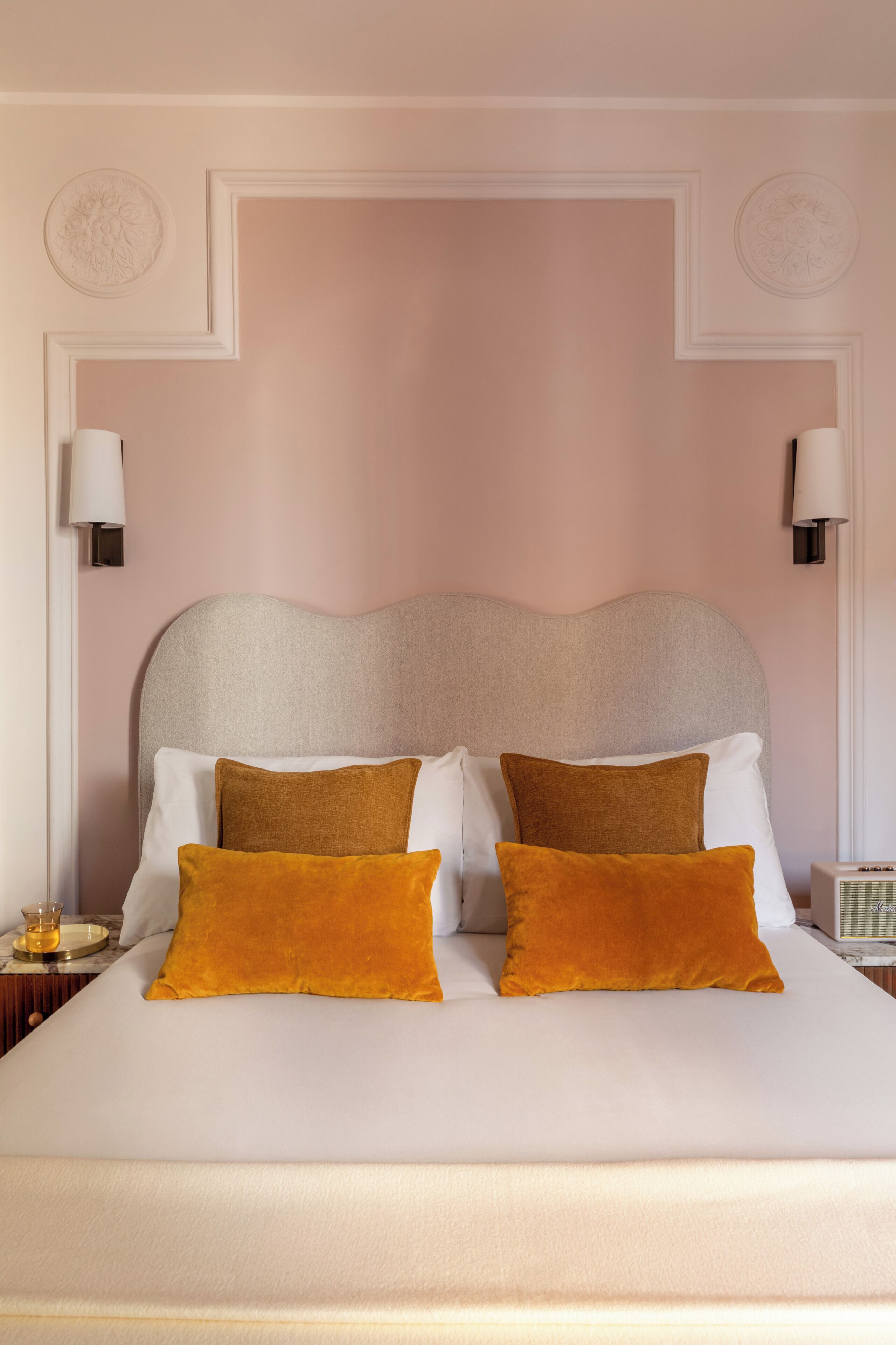 A bed with a headboard, two bedside lamps, and a nightstand with a lamp.