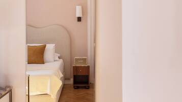 A bedroom with a bed, bedside table, lamp, and a mirror reflecting the room.