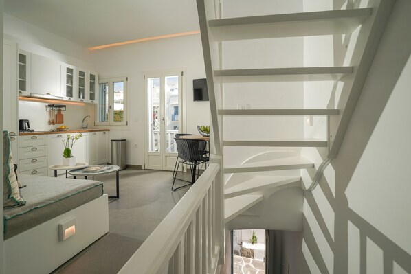 A modern kitchen with white cabinetry, a dining area with a round table, and a staircase leading to an upper level.