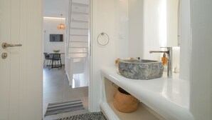 Un baño moderno con lavamanos de mármol, un aro para toallas y un espejo.