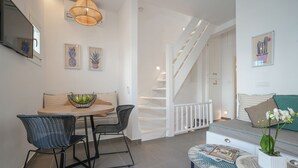 Un interior moderno con comedor, escalera y zona de estar con sofá y mesa.