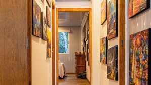 A hallway with wooden floors and walls adorned with framed artworks. - La Ballena Nómada (Akumal)