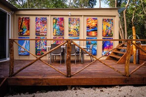 A wooden deck with a railing, surrounded by colorful paintings on the walls. - La Ballena Nómada (Akumal)