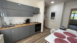 A compact kitchen with grey cabinets, a wooden countertop, a sink, and a coffee maker.
