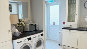 A laundry room with a Bosch washing machine and dryer, a microwave, and a cabinet with glassware.