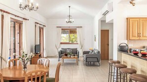 A spacious living area with a dining table, sofas, and a kitchen area with stools.