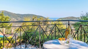 Terraço com mesa posta para dois, com vista para uma paisagem montanhosa.