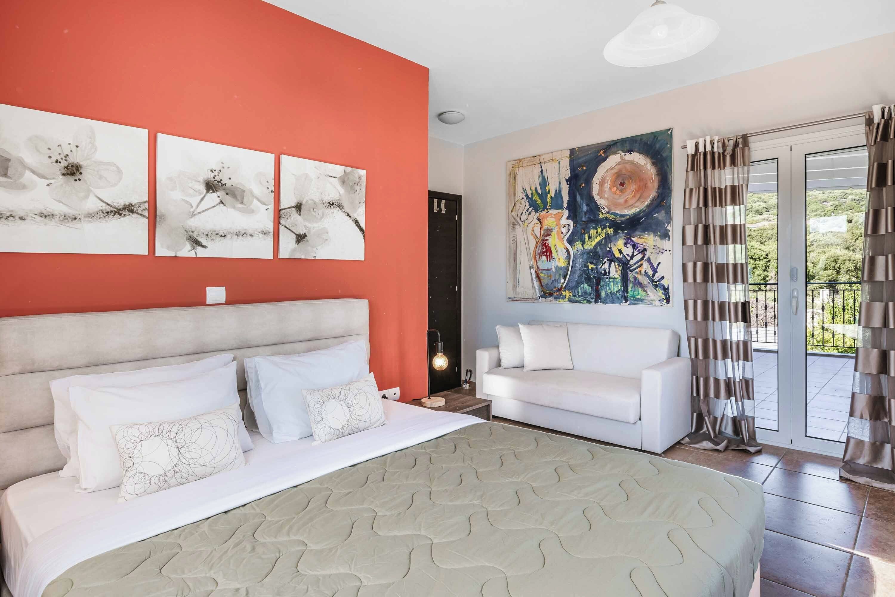 Een slaapkamer met een groot bed, een witte bank en kunstwerken aan de muur.