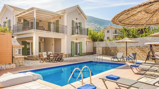 Uma casa de dois andares com piscina, móveis de exterior e montanhas ao fundo.