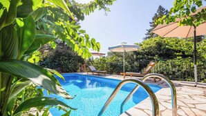 A swimming pool with clear blue water, surrounded by lush greenery and a tiled deck. - Stone Cottage - Two Bedroom Villa, Sleeps 4 (Nisaki)