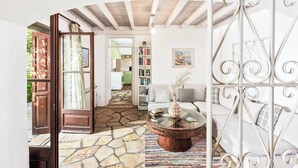 A spacious living area with a stone floor, a round coffee table, a white sofa, and a bookshelf. - Stone Cottage - Two Bedroom Villa, Sleeps 4 (Nisaki)