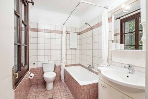 Een badkamer met toilet, bad en wastafel.