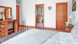 A bedroom with a bed, wooden dresser, and a desk. There is a mirror above the dresser and a door leading to a bathroom. - Villa Ash - Four Bedroom Villa, Sleeps 8 (Alcantarilha)