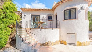 A white stucco building with a tiled roof, a balcony with chairs, and a staircase leading to the entrance. - Villa Abeto - Two Bedroom Villa, Sleeps 4 (El Tosalet)