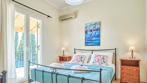 Ein Schlafzimmer mit einem Bett, zwei Nachttischen, einem Gemälde und einer Glastür zu einem Balkon.