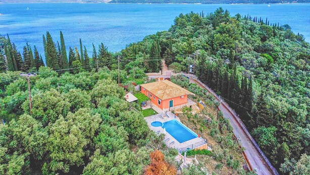 Ein Haus mit Schwimmbecken, umgeben von Bäumen und mit Blick auf ein Gewässer.