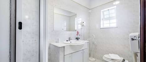 A bathroom with a white sink, mirror, and toilet.