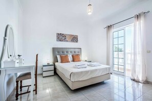 Ein Schlafzimmer mit einem Bett, Nachttischen, einem Spiegel und einem Fenster mit Vorhängen.