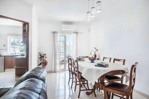 A dining area with a white table, wooden chairs, and a black leather couch. - Villa Arcadia - Eight Bedroom Villa, Sleeps 16 (Vale Rebelho)