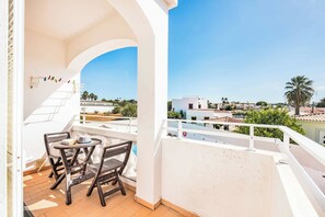 A balcony with a table and chairs, overlooking a residential area with houses and palm trees. - Villa Arcadia - Eight Bedroom Villa, Sleeps 16 (Vale Rebelho)