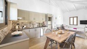 A modern kitchen with a wooden dining table, white cabinets, and a patterned backsplash.