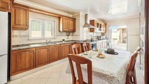 Une cuisine moderne avec des meubles en bois, un plan de travail en granit et un coin repas avec une table dressée pour deux personnes.