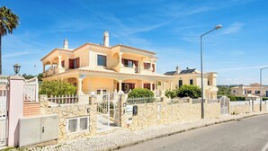 Une maison à deux étages avec une façade en pierre, de nombreux balcons et une allée pavée.