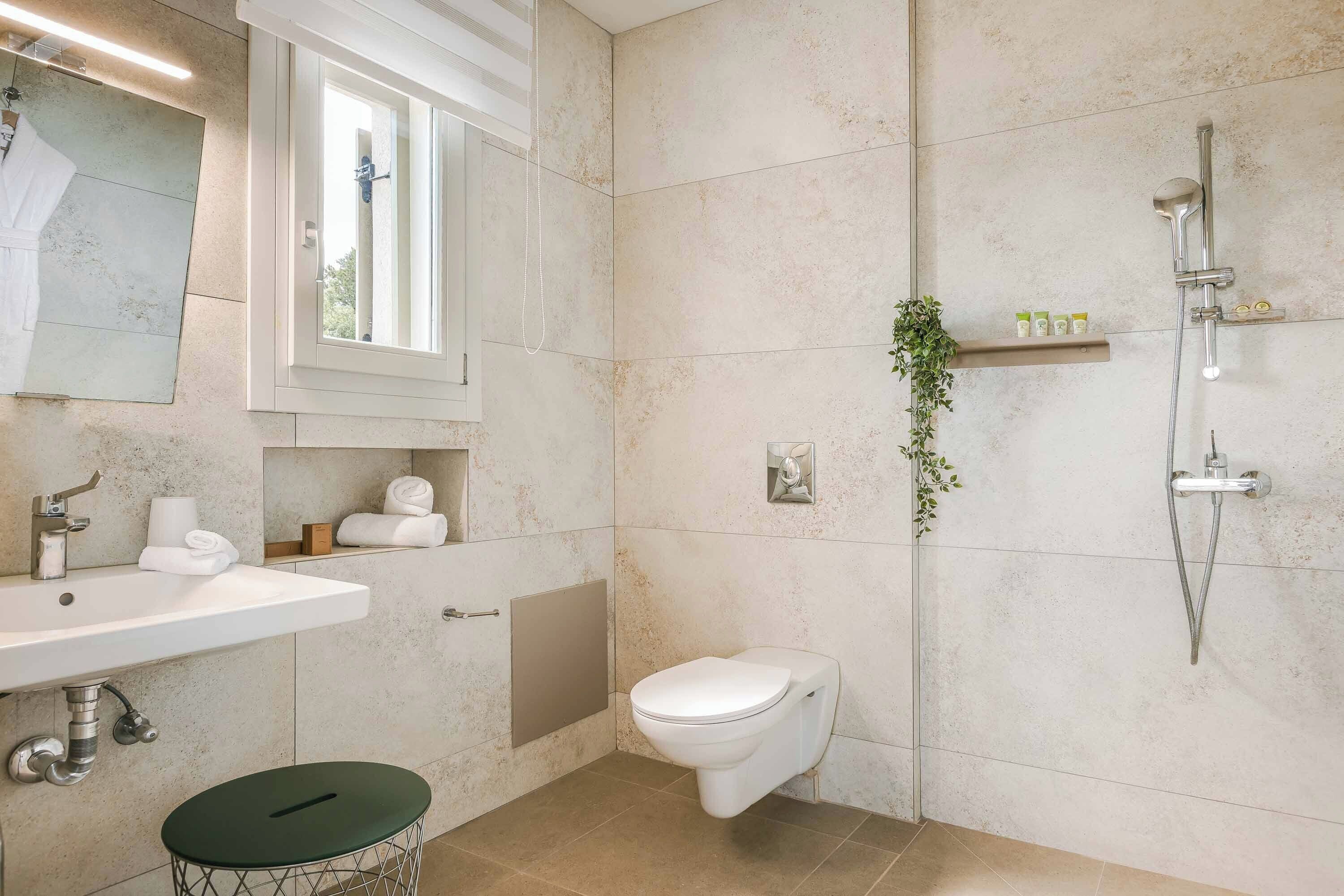 Et moderne badeværelse med vask, toilet og brusebad.