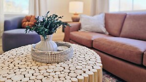 A living room with a round wooden coffee table, a white vase with green plants, a brown sofa, and a grey armchair. - NEW! Hot Tub, Firepit & Game System Near Hershey - Walk To Lake & Fishing! (Lebanon)