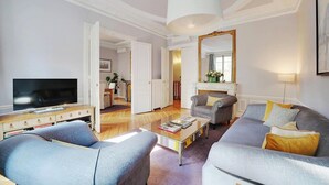 A living room with a television, two armchairs, a sofa, a coffee table, and a fireplace. - NESTLED IN THE HISTORIC LATIN QUARTER,JUST STEPS FROM THE SEINE RIVER&NOTRE-DAME (Paris)