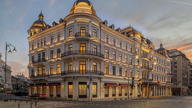 Un edificio histórico y majestuoso con el nombre "CORINTHIA" bien visible. Destaca por su arquitectura clásica, con varios balcones y amplias ventanas.
